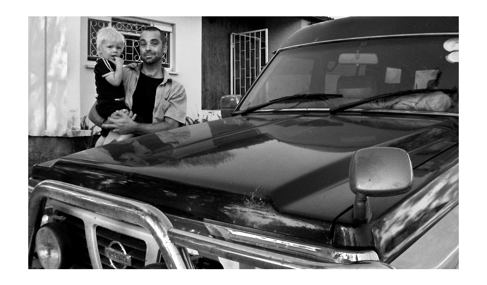 Nick Dunkerley, founder of Hindenburg Systems, standing with his son in front of their home in Zambia beside his Nissan Patrol