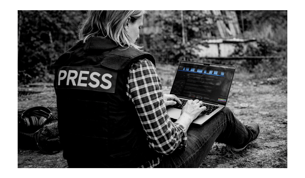 War correspondent sitting behind the front line editing an interview on a laptop using Hindenburg Pro, illustrating how journalists can produce audio stories offline in difficult field conditions.