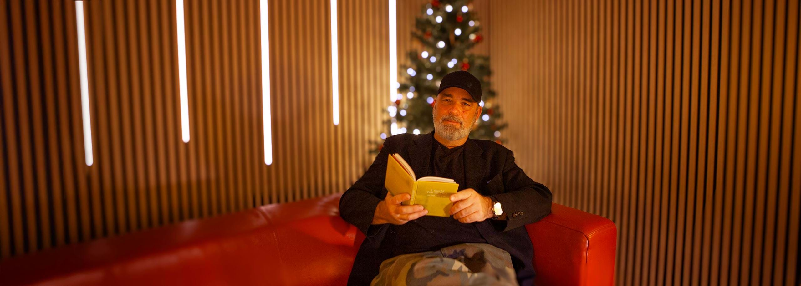 Founder Hindenburg Systems Nick Dunkerley Reading Loud in Sound Studio for Christmas Calendar 2024 at Couch with Christmas Tree in the background 