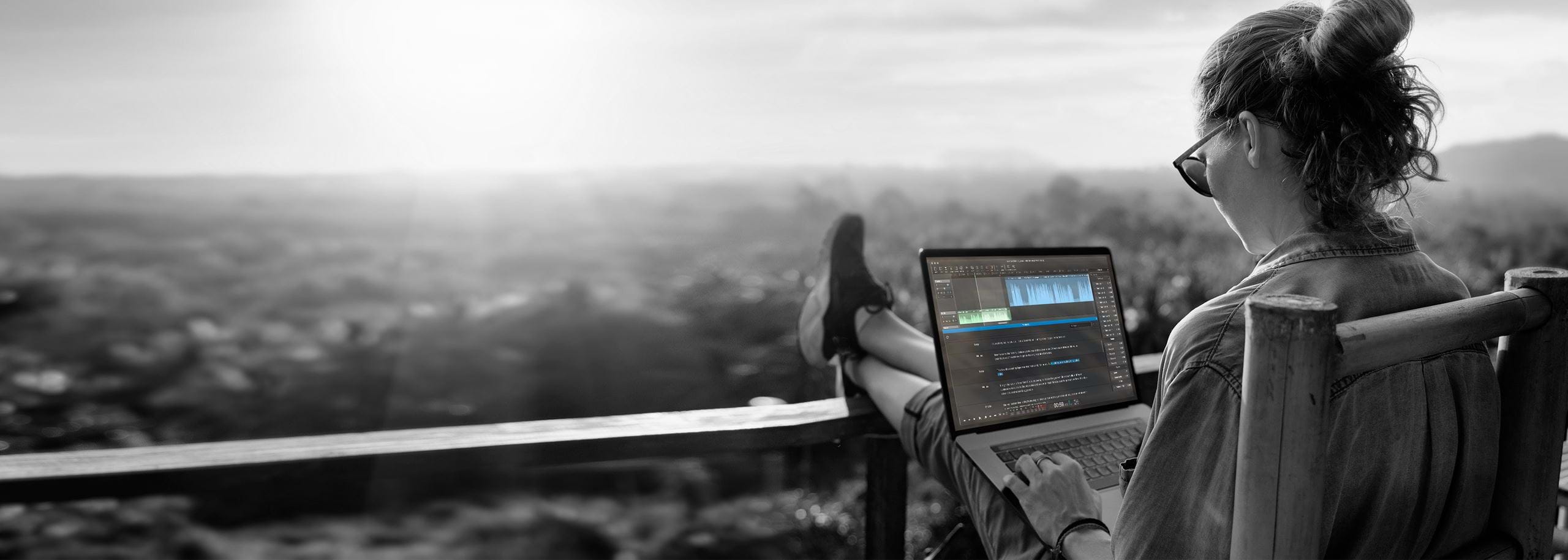 A journalist editing an audio story in Hindenburg Pro while working outdoors above a forest landscape. Built for storytelling, Hindenburg enables professional audio editing anywhere — even offline.