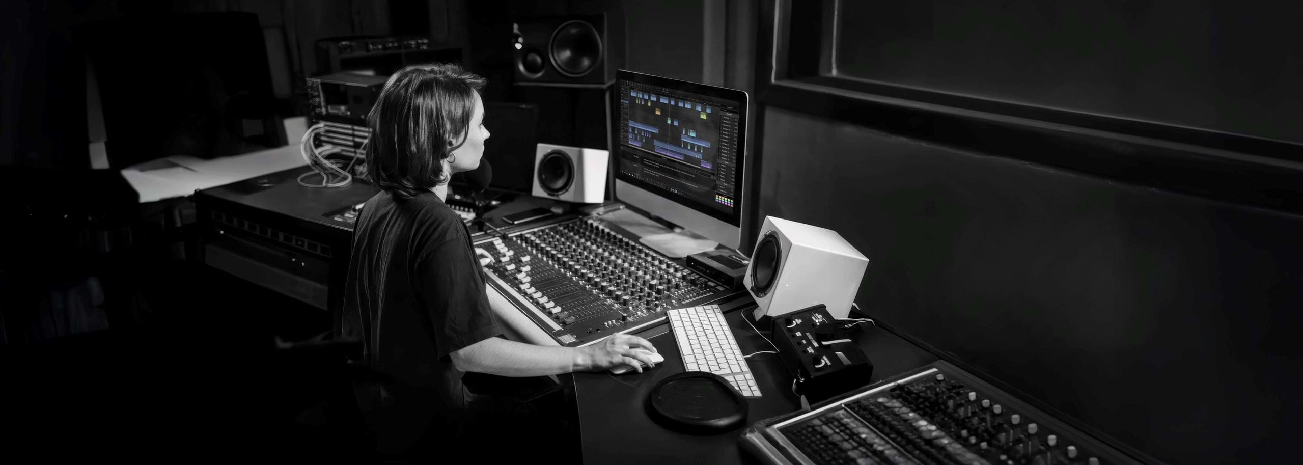 Audio journalist editing a story in Hindenburg Pro on a computer screen in a professional audio production studio.