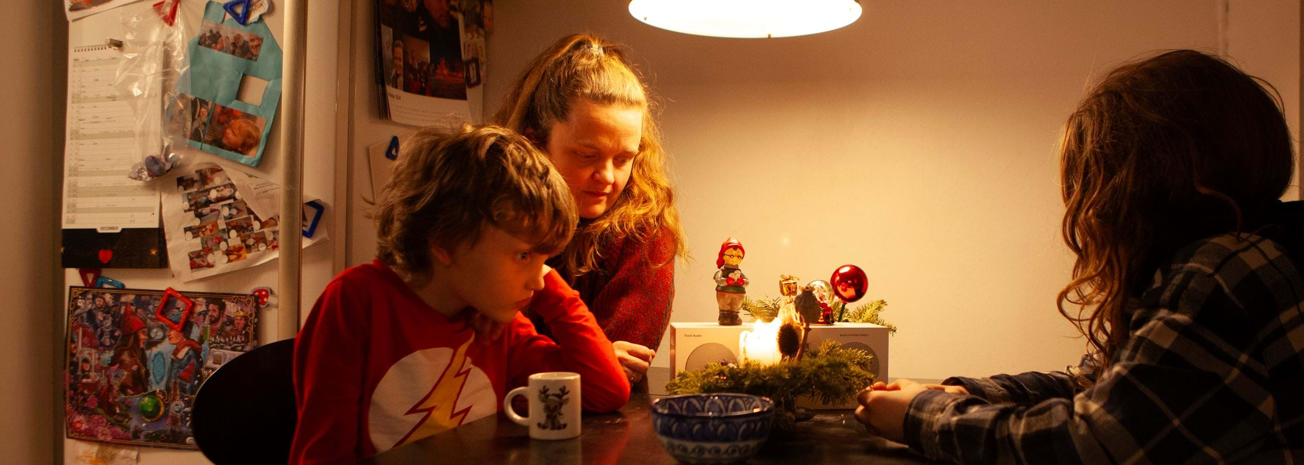 Scandinavian Mother with her two Boys Listening to Podcast on small Radio in a cosy Christmas Kitchen Environment Hindenburg Systems