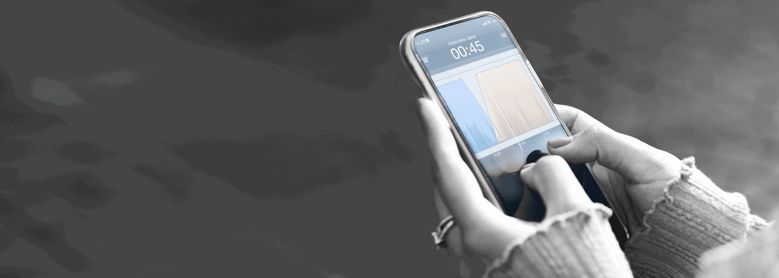 Hands holding a smartphone showing the Hindenburg Field Recorder app with an audio waveform and editing interface visible.